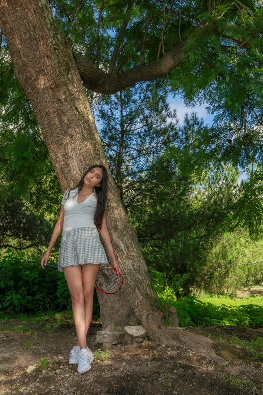 a young woman in a white dress standing under a large tree