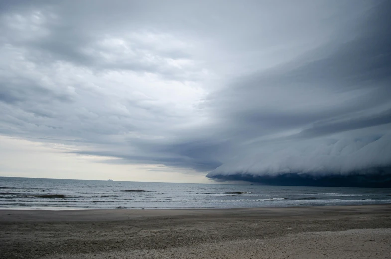 a storm rolls over the ocean and beach as it begins to come down