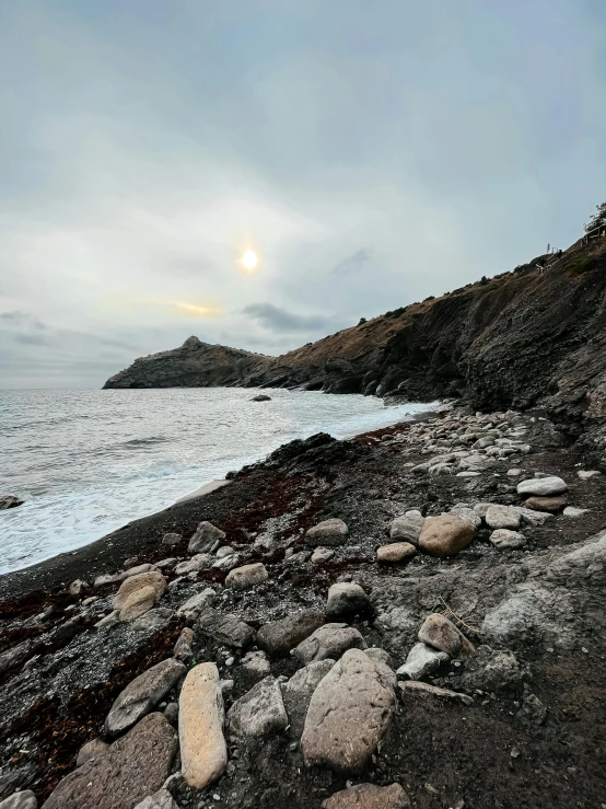 the shore of an island on the coast is shown in a cloudy sky