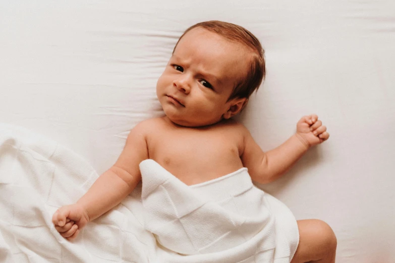 a baby wrapped up in a towel sitting on the bed