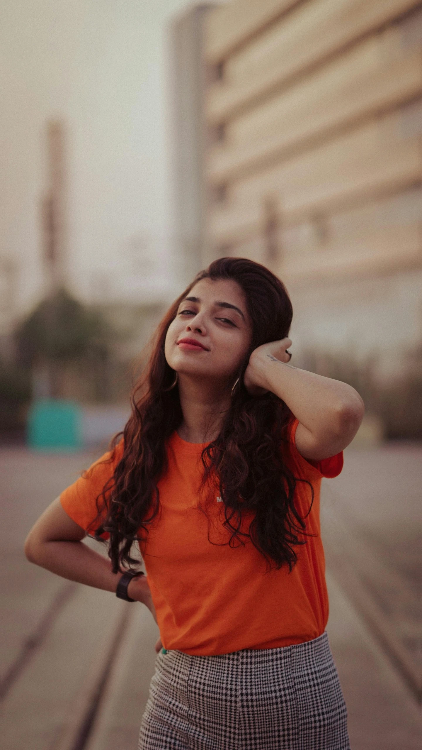 a girl poses while looking upward wearing an orange shirt