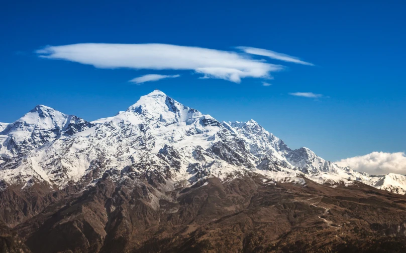 a large snow capped mountain sitting below a blue sky