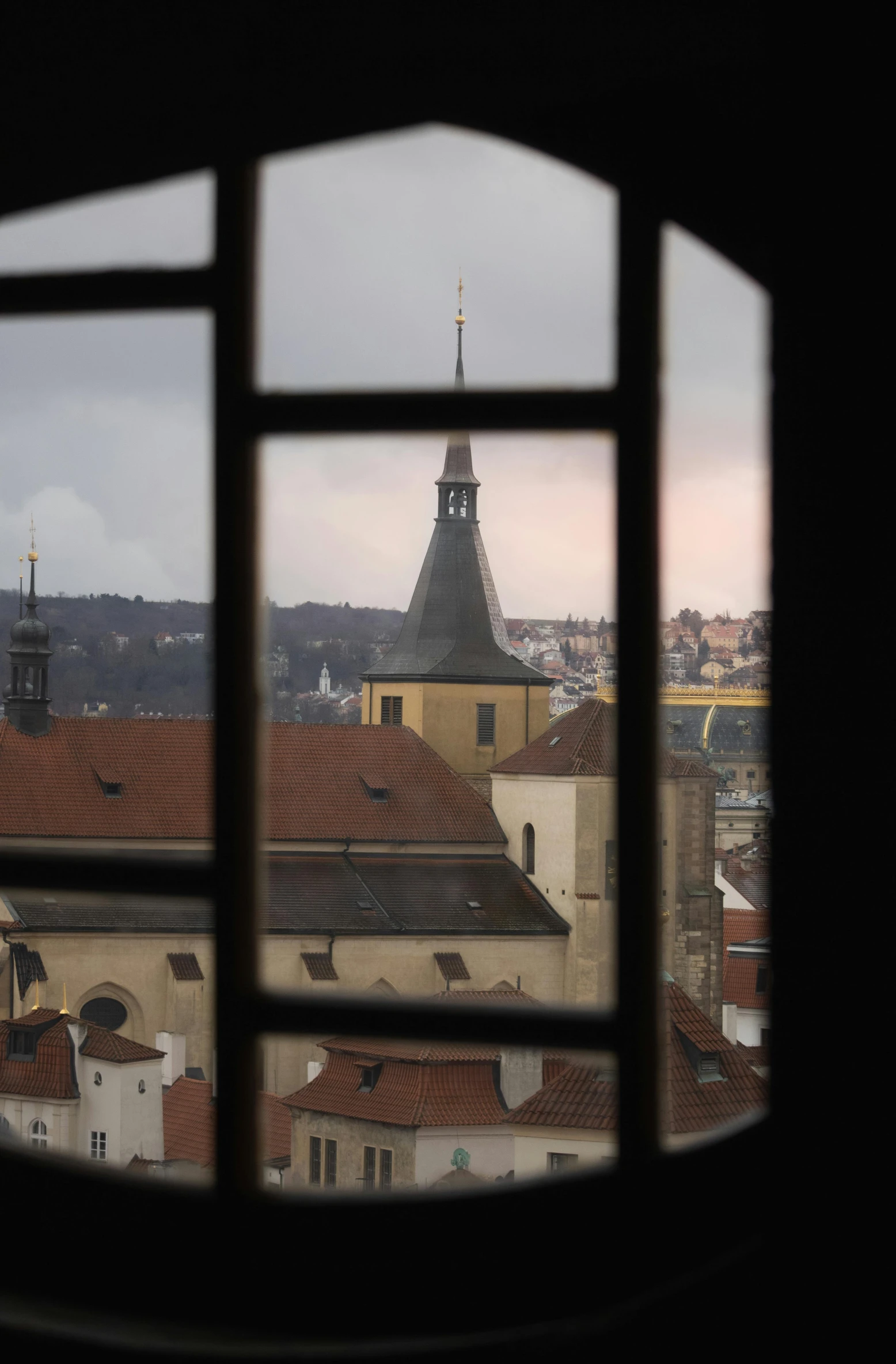 view of rooftops through window of old building