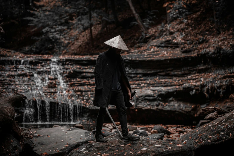 a man wearing a hat with his back turned is standing on a rock