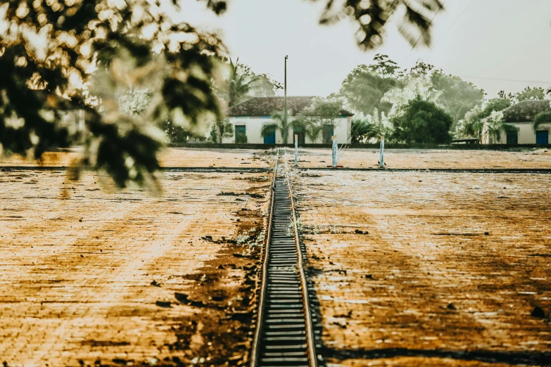 train track running alongside a brick area with house in background