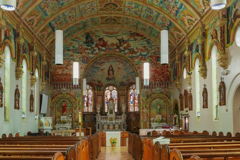 a large cathedral has a colorful ceiling and stained glass windows