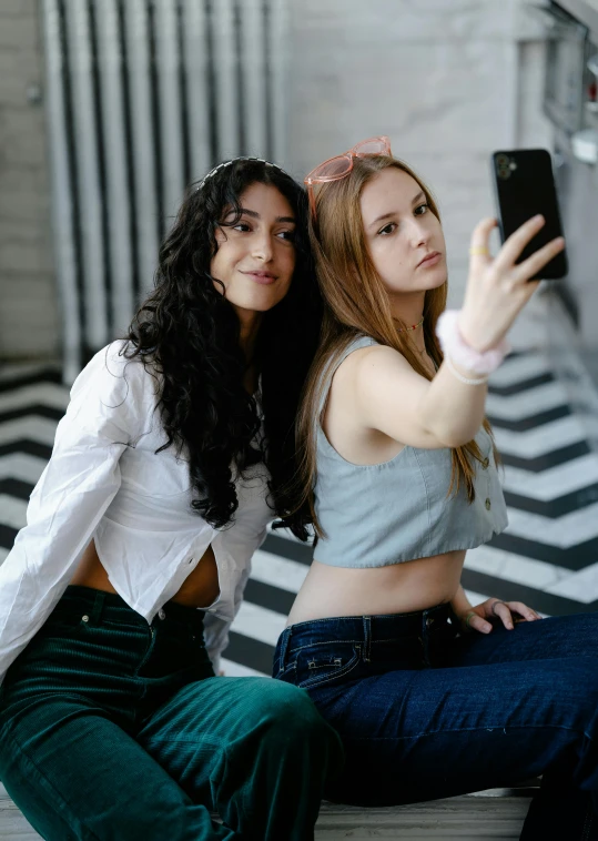 two women taking a selfie while sitting on the floor