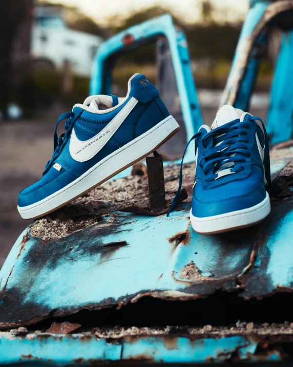two sneakers are worn on a rusted blue piece of metal
