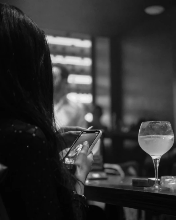 a woman looking at her phone while drinking wine