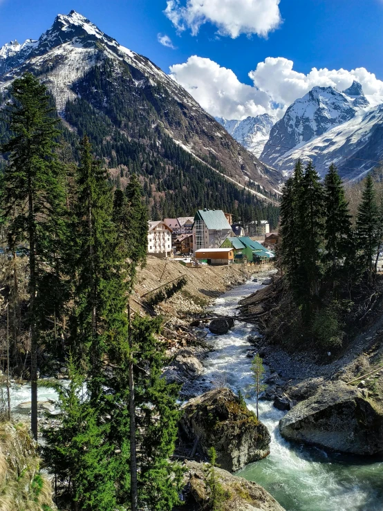 a mountain town sits on a hillside near a river