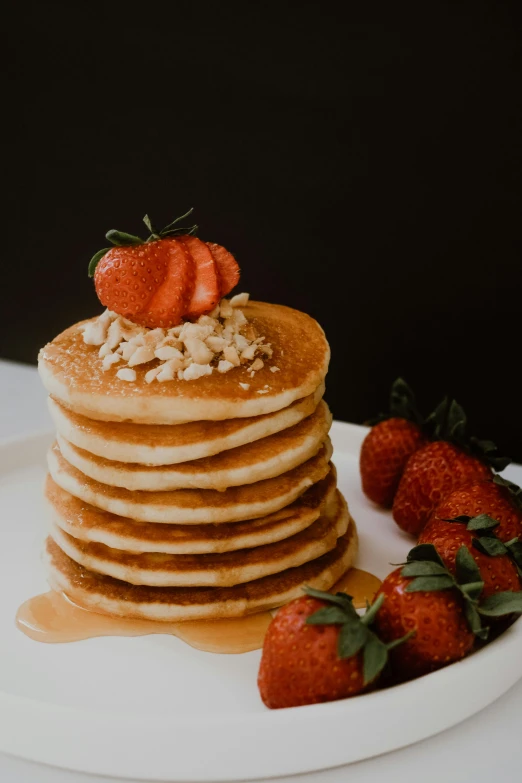 a stack of pancakes and strawberries is topped with a cherry