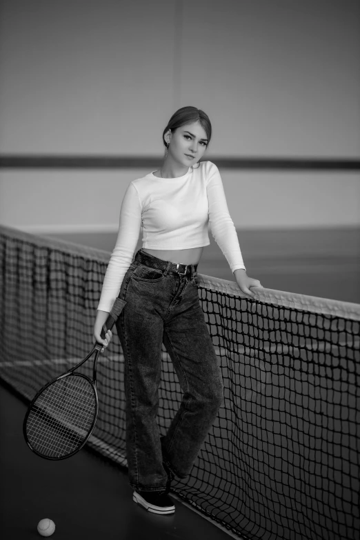 a young woman with a tennis racket leaning on a tennis net