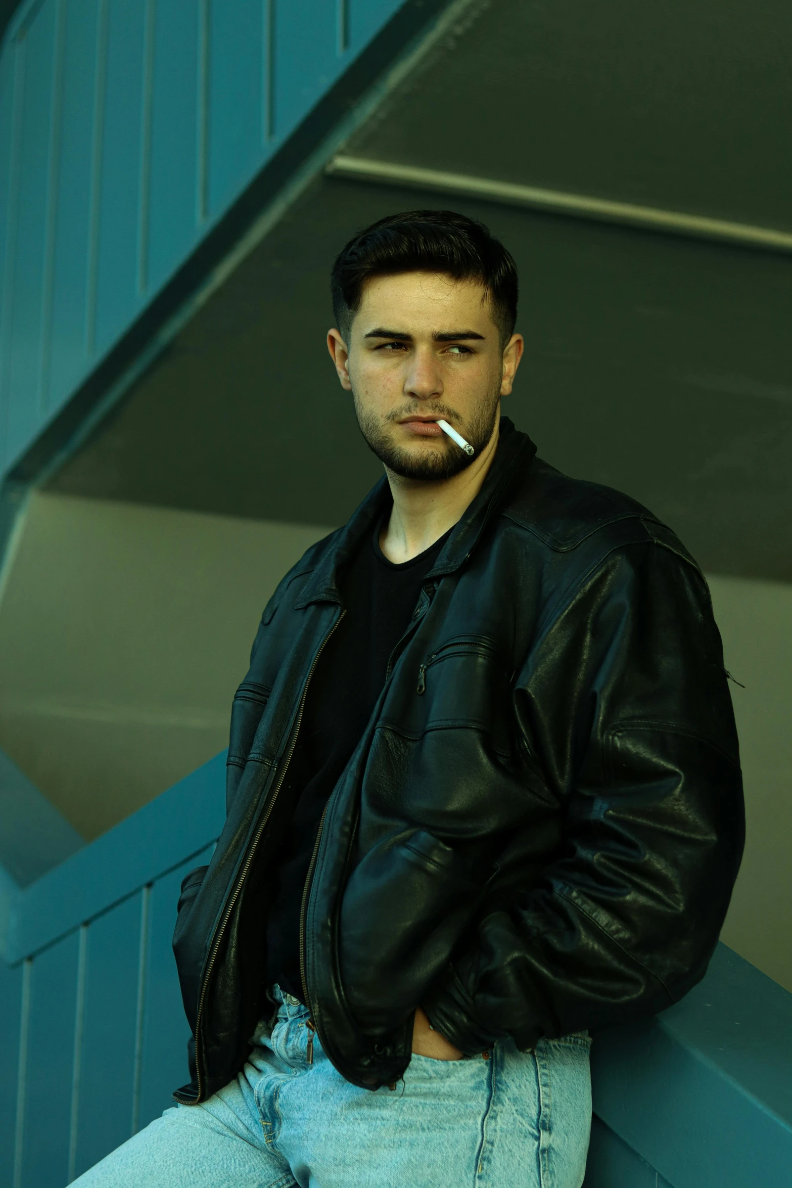 a man in leather jacket smoking a cigarette