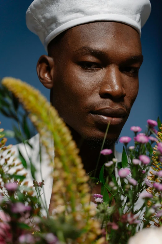 a black man with a white hat and colorful flowers