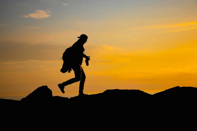 the silhouette of a woman on top of a mountain at sunset