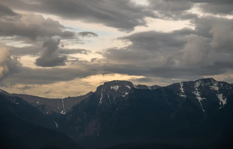 a jet flying above some mountains with clouds