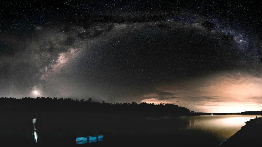 stars fill the night sky above a body of water