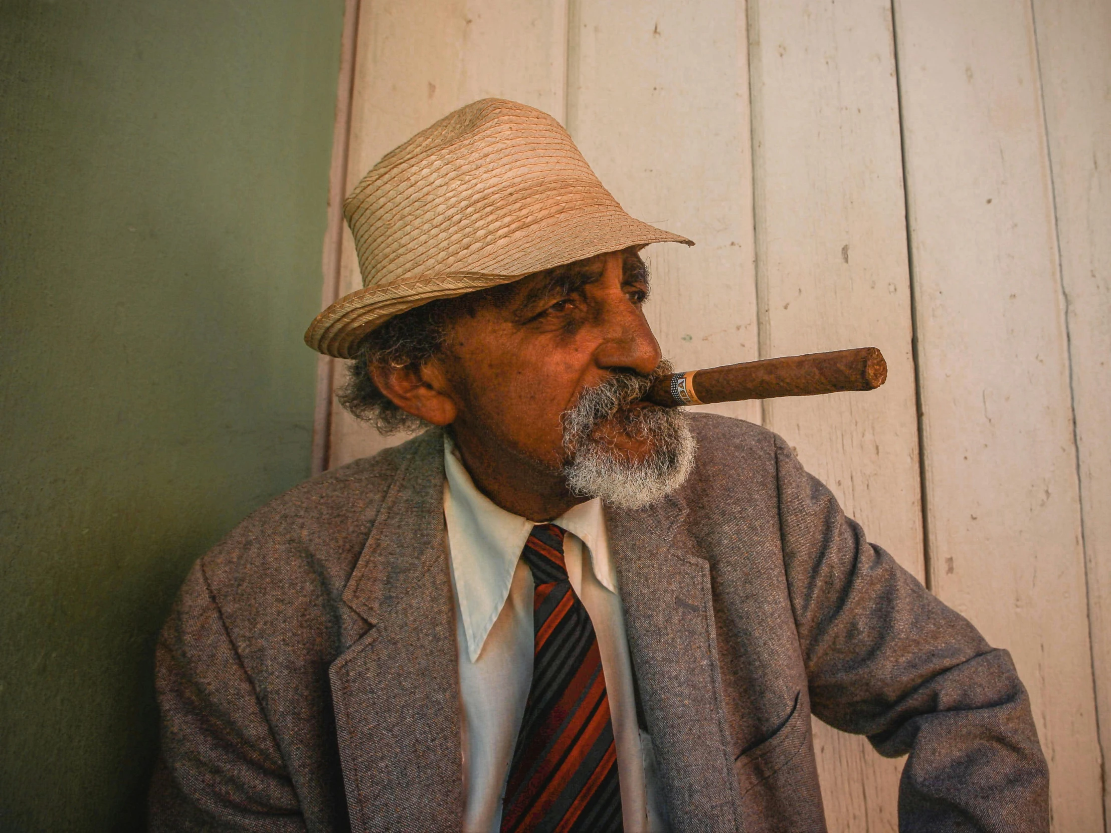 a man wearing a suit jacket and tie with a long cigarette