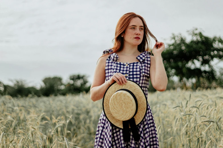 a woman in a field holds onto a hat