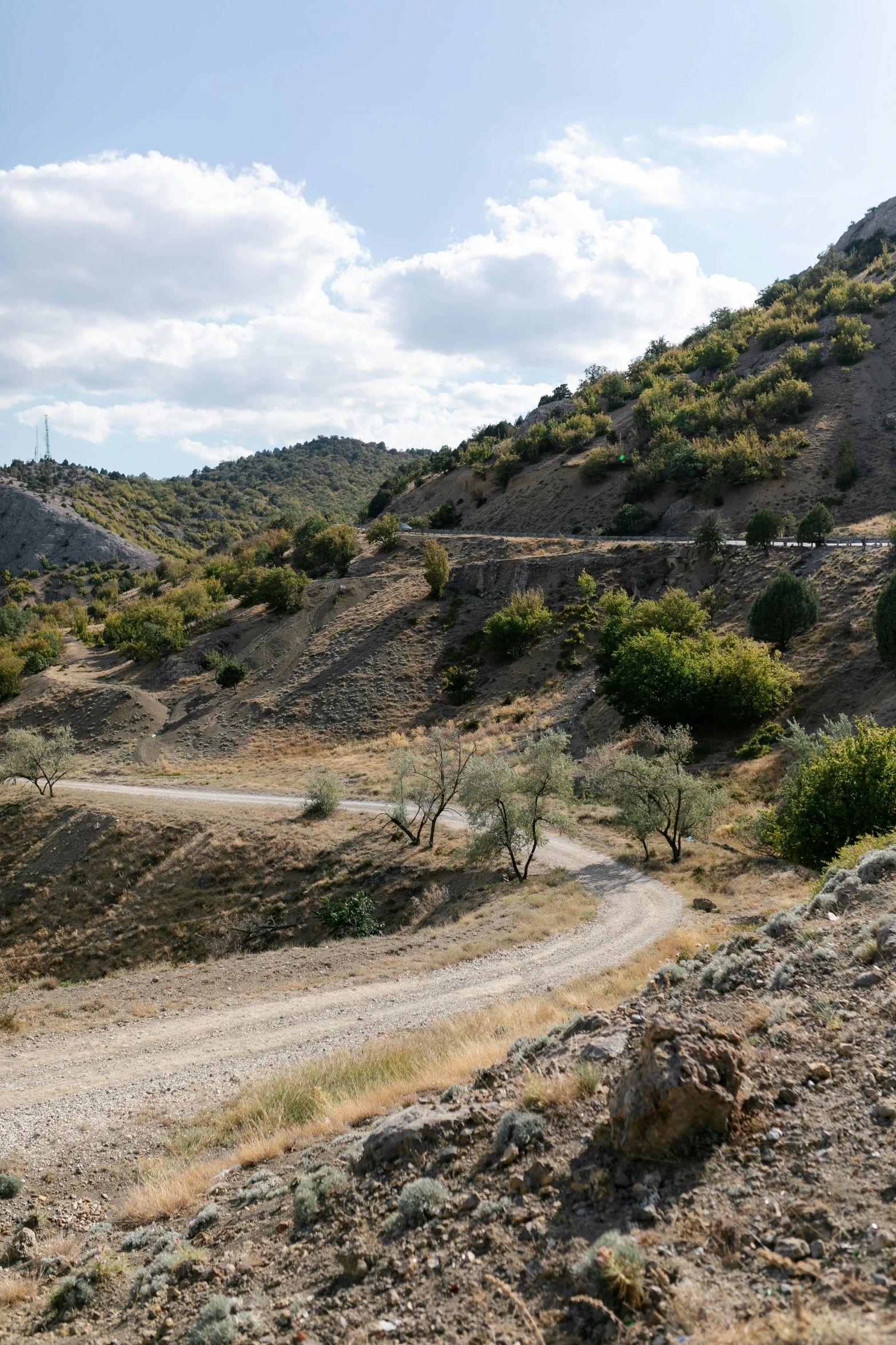 an empty dirt road winds through a barren hill