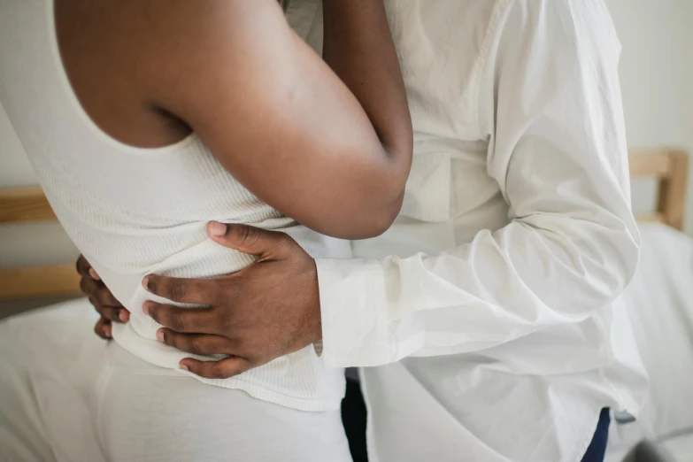 a couple in white are hugging on the bed