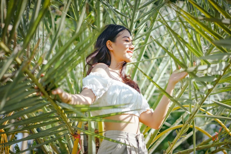 a woman standing in a palm tree forest holding soing