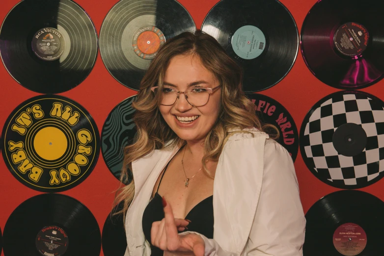 a woman points at a wall made up of old records