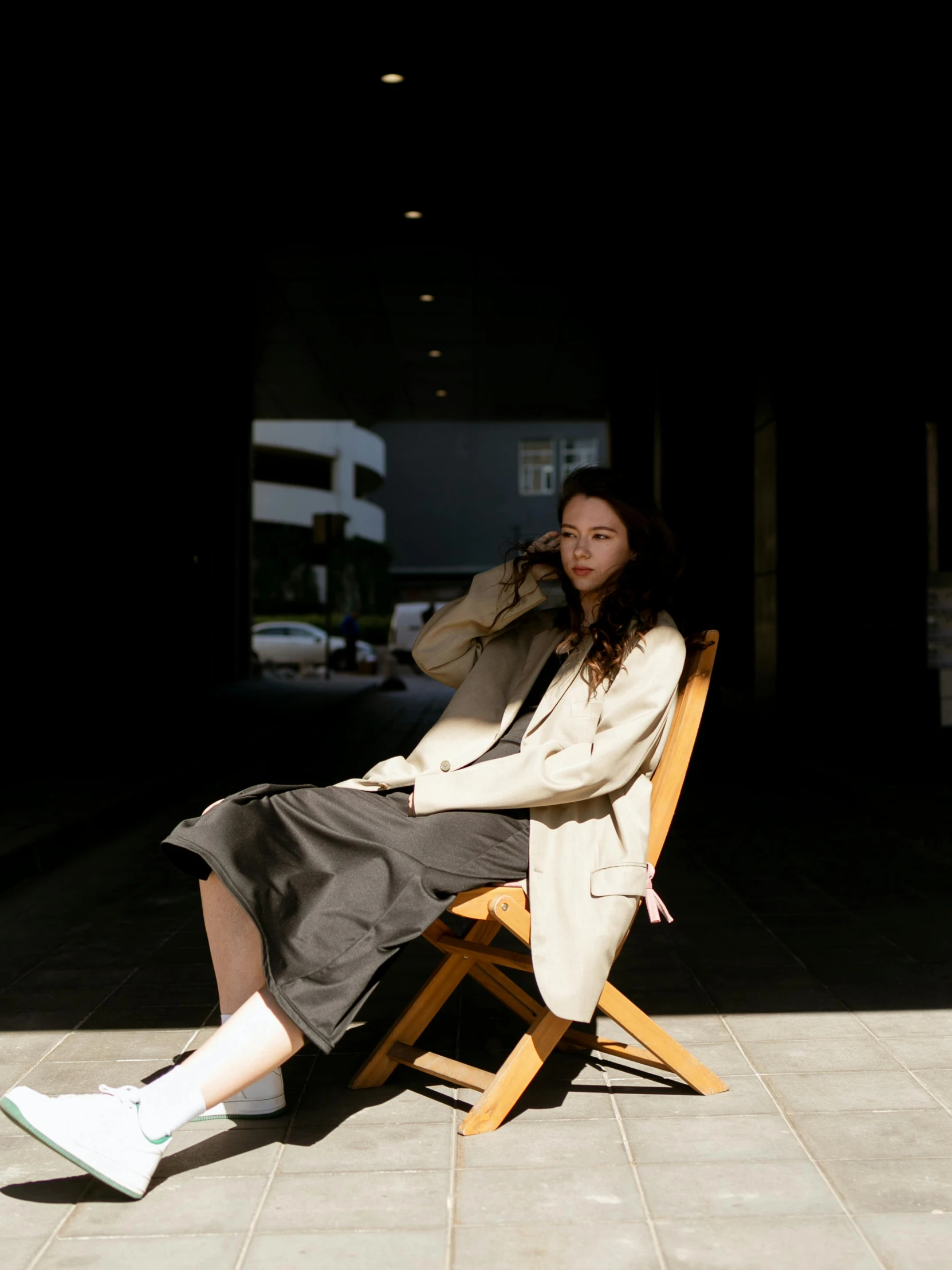 a woman sits on a wooden chair posing for a po