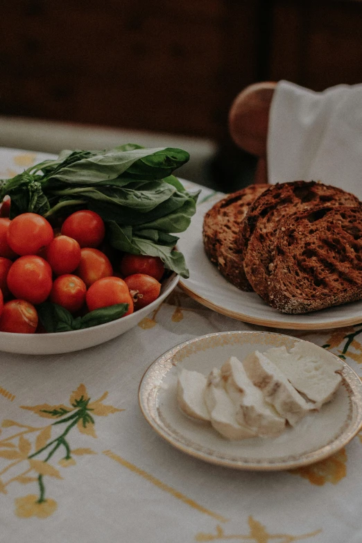 bread, tomatoes and spinach on plates sit in front of a plate of salad