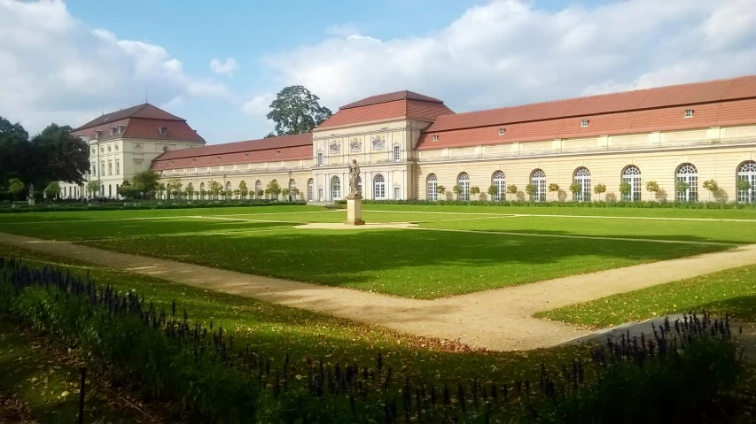 the grass lawn of a large building has a walkway in front of it