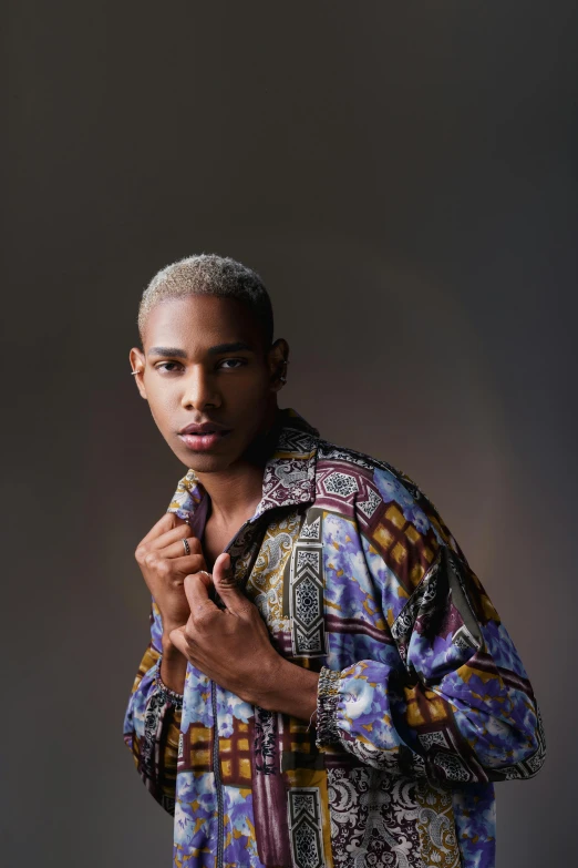 an african american male wearing a patterned shirt posing for a pograph