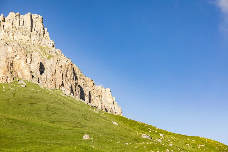 a grassy hillside with some very tall rocks on the top