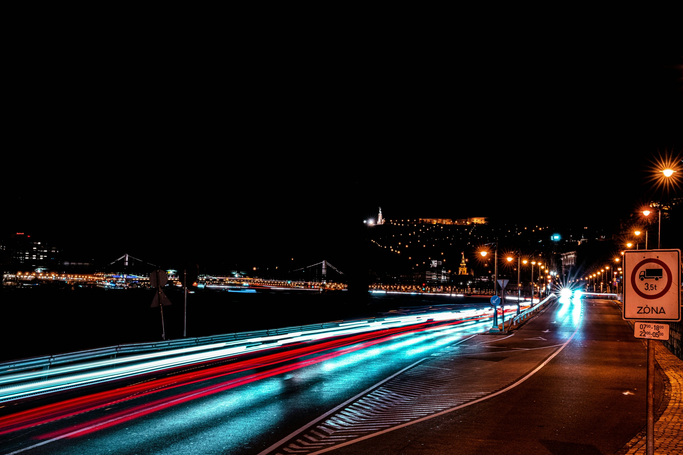 cars move along a city street with their headlights streaking past