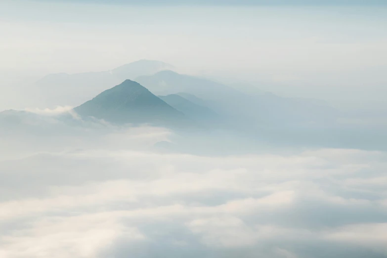 a hill covered in cloud sitting on top of a sky filled with clouds