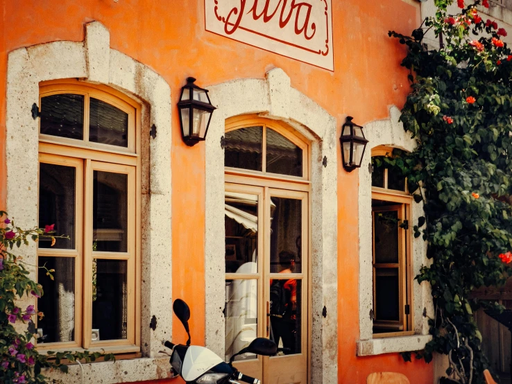an orange building that has some windows near a scooter