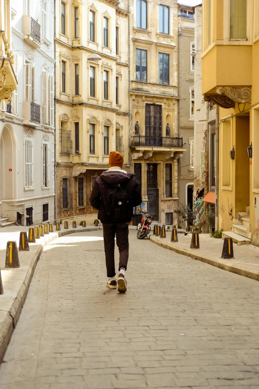 the guy is walking up the street with his back pack