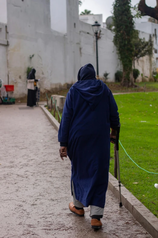 an old woman with an umbrella walks in the rain