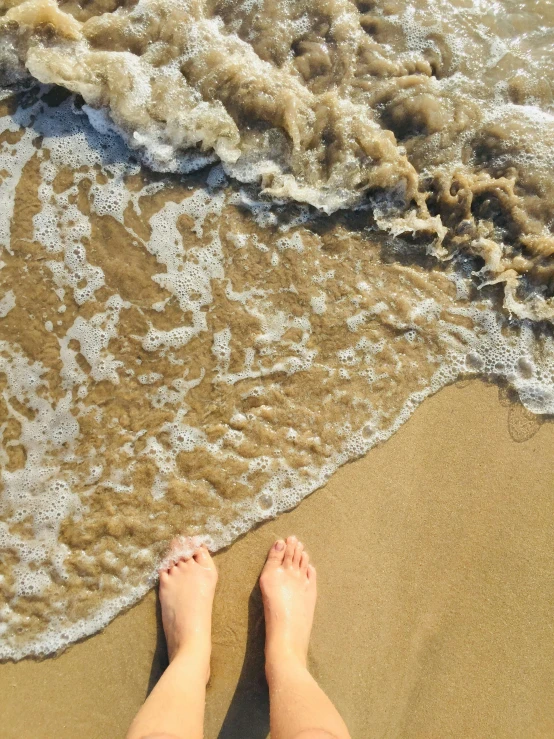 the legs and legs of a person standing on the beach