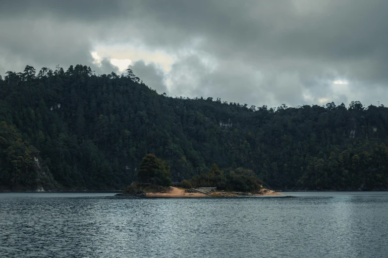 an island is out in the middle of a lake surrounded by hills