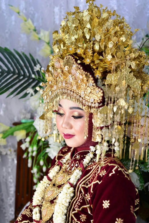 a young female dressed in a dress with flower garland and gold head piece