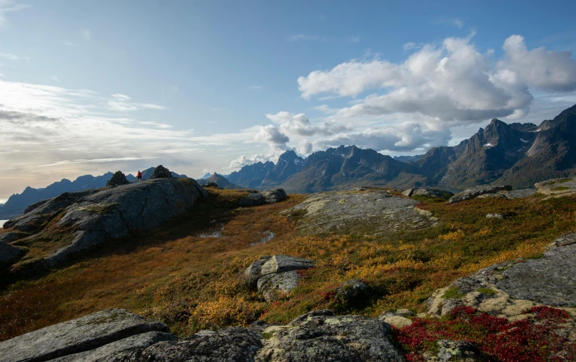 two people hiking up a mountain side, with mountains in the background