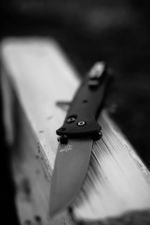 a knife sits atop a piece of wood