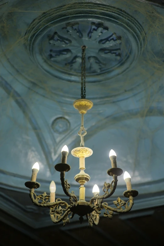 several candle lights on a ceiling that is made out of a fancy patina