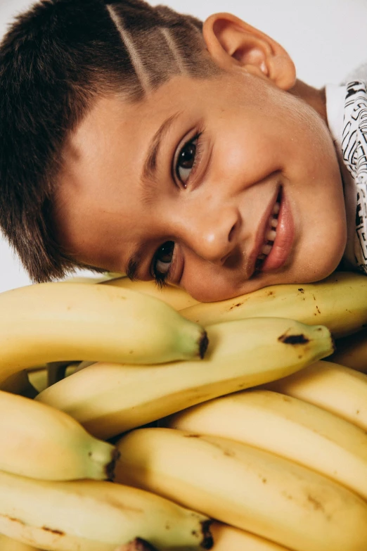 the  smiles and rests his head on top of the bunch of bananas