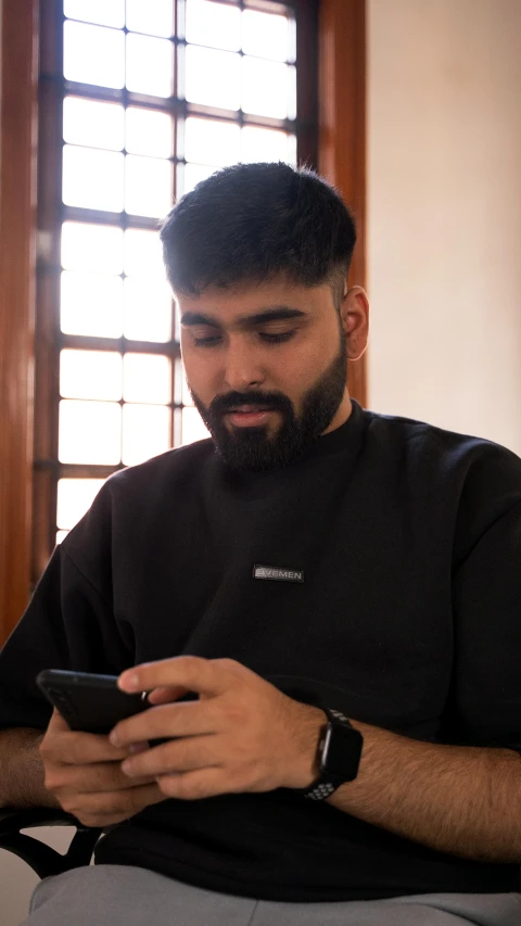 the man is typing on his cellphone in a room