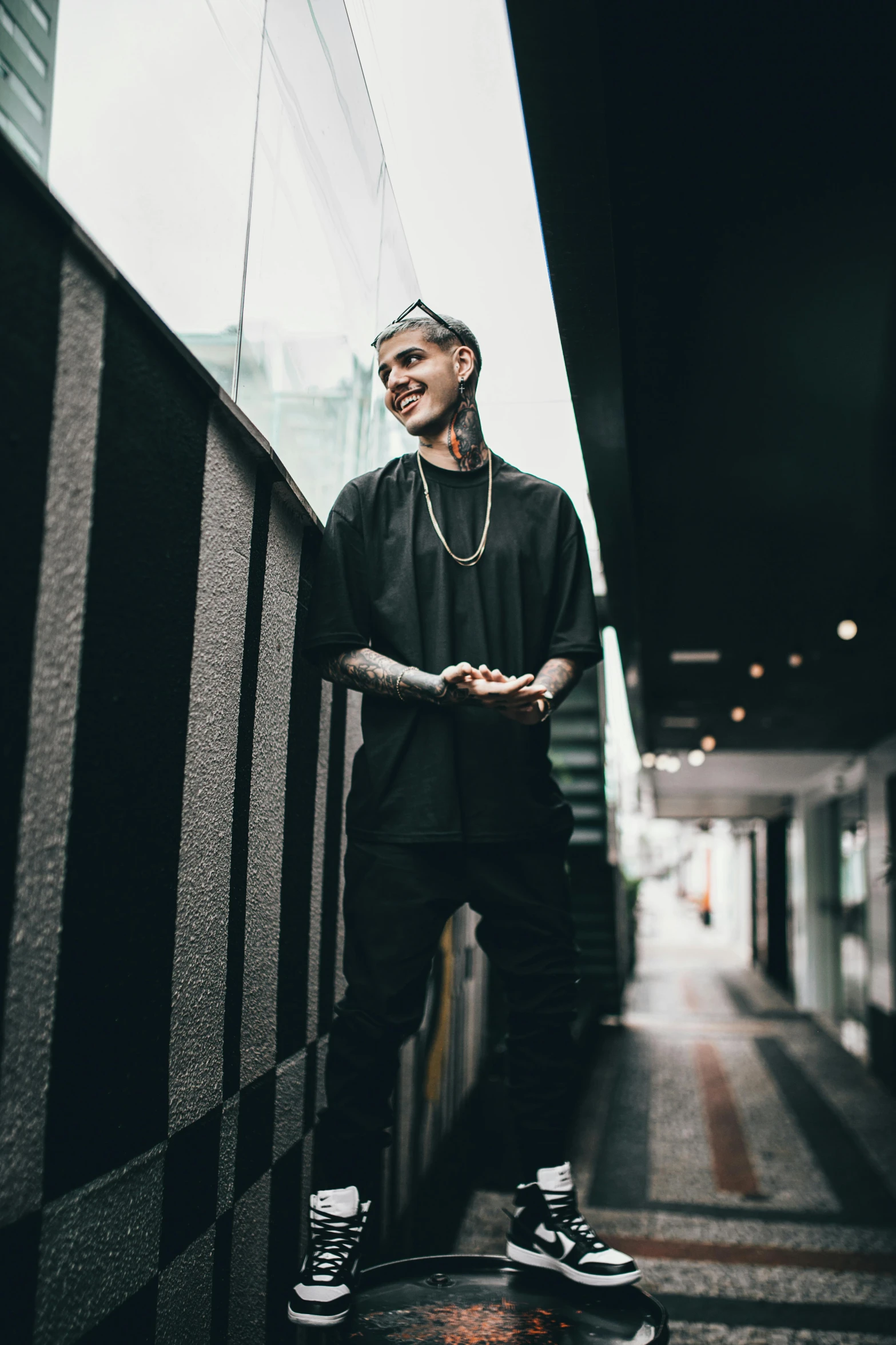 a young man with tattoos and piercings posing on a skateboard