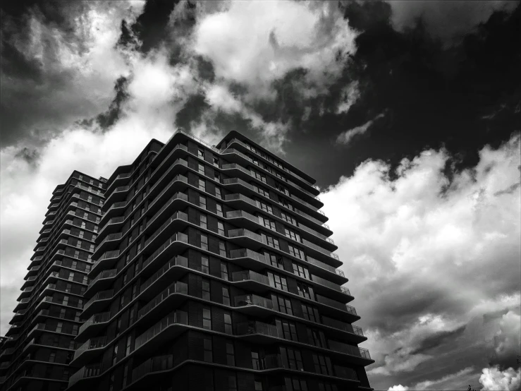 a tall building with balconies on the windows under some cloudy skies