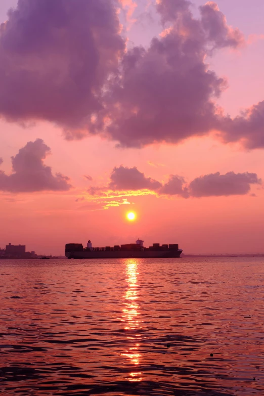 large cargo ship floating in the ocean at sunset