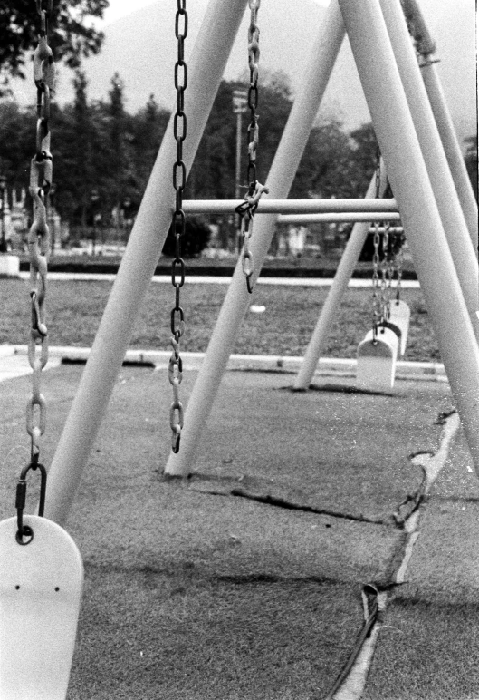 empty swing frames in black and white at a playground