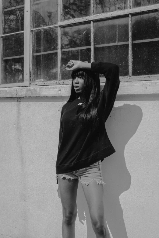 a young woman stands against a wall and wears black sweater